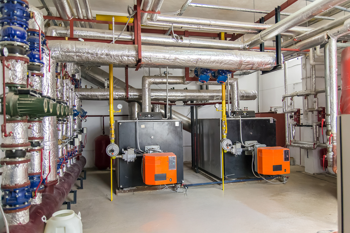The industrial power cogeneration units with extensive piping in a clean utility room.
